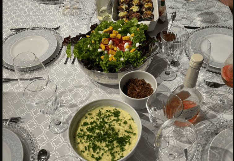 Mesa posta com salada, outros pratos, taças e louça